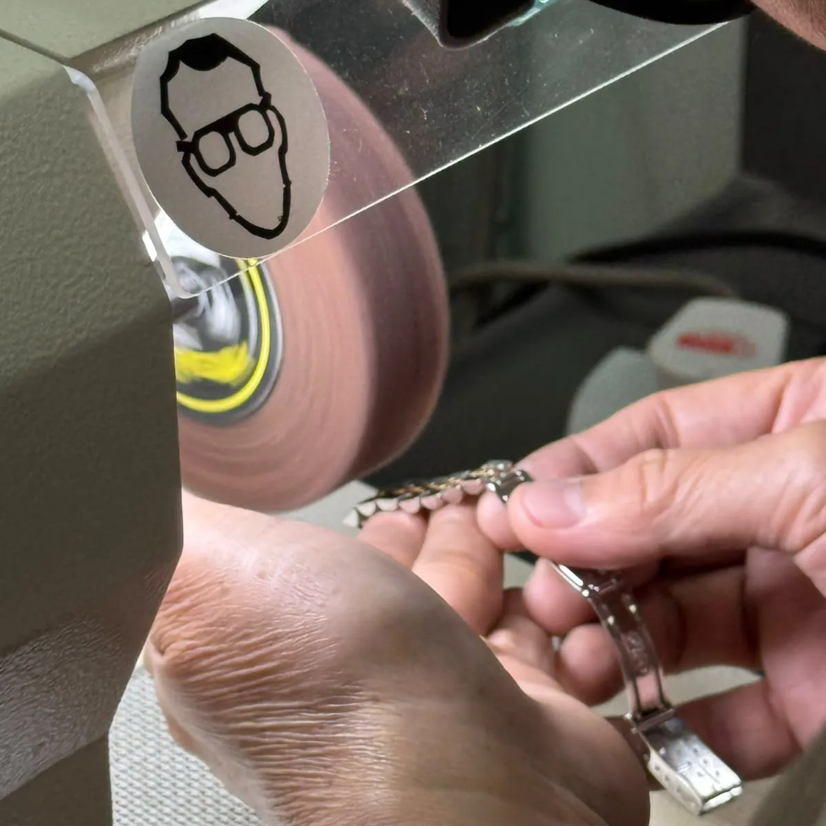 A watchmaker polishing a bracelet on the lathe