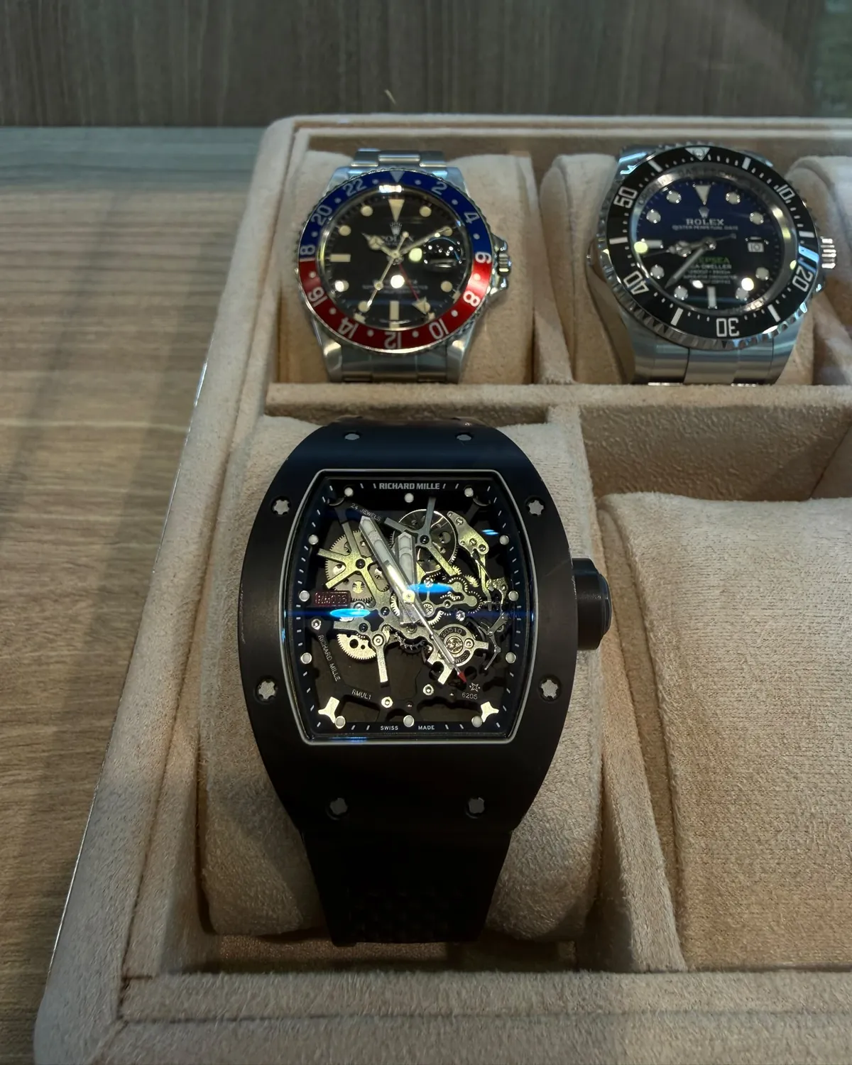 Three watches resting on the cushions of a suede watch tray