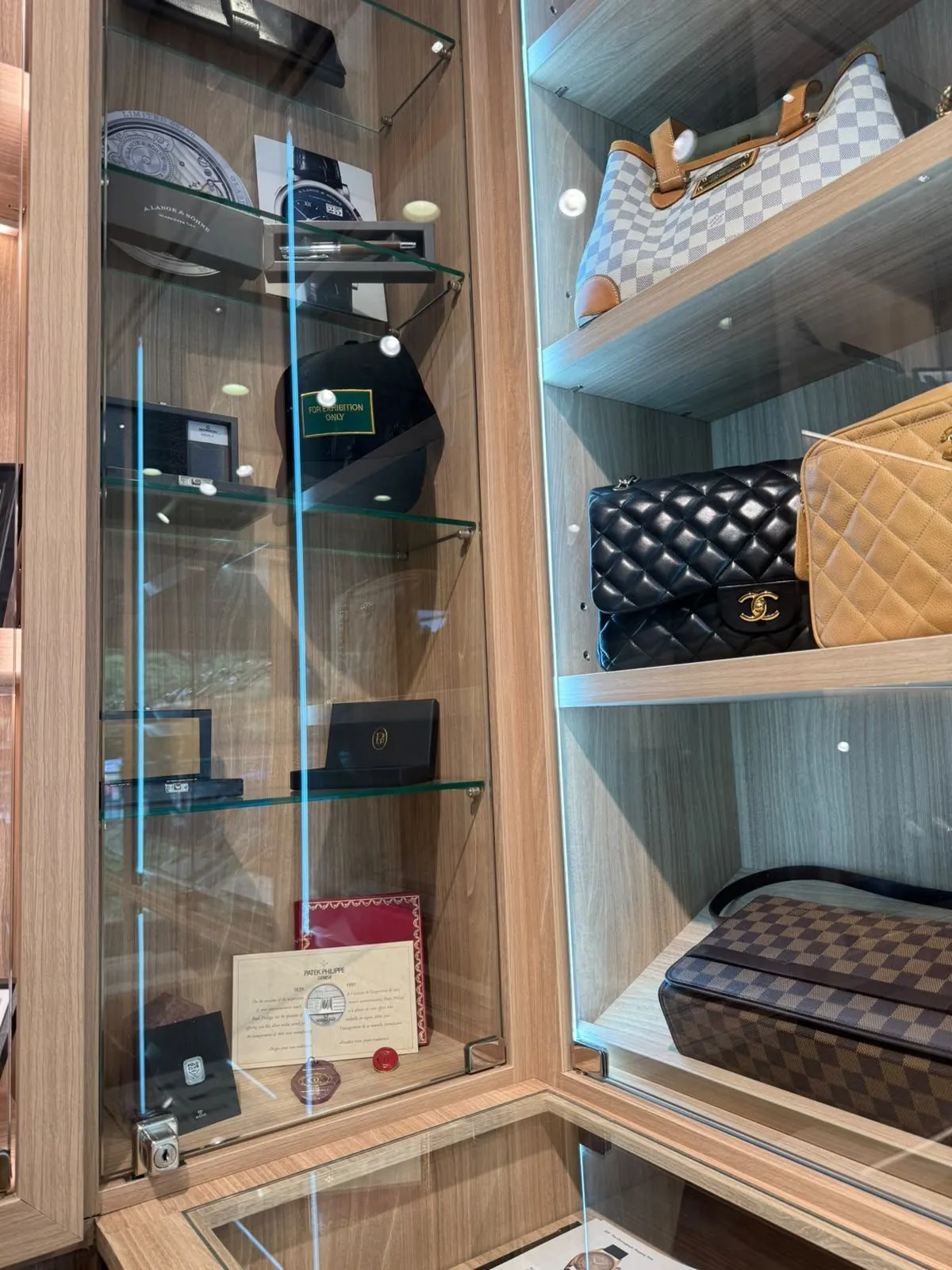 The cabinet at the atelier: pre-owned handbags beside watch-brand boxes and papers