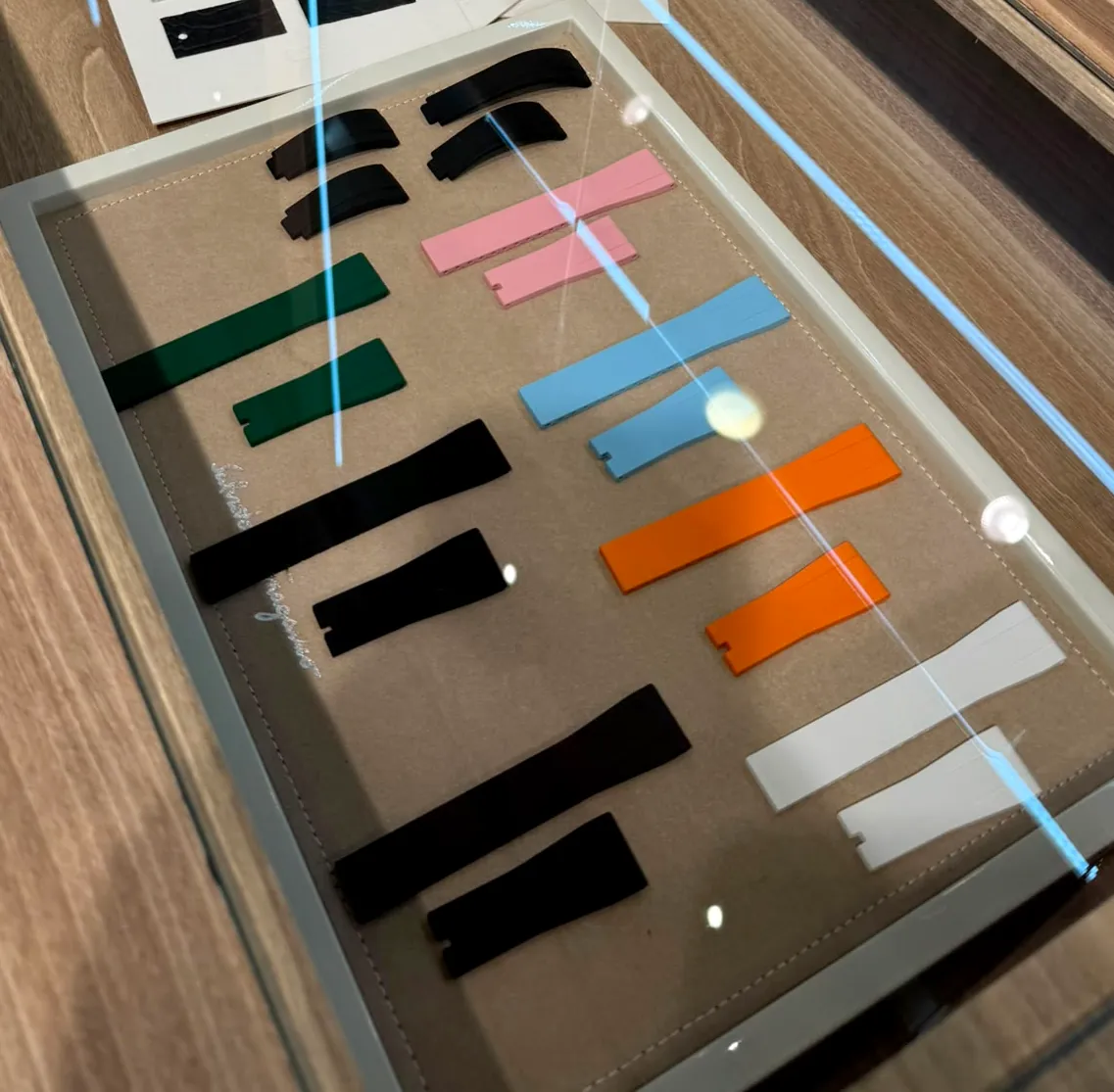 A tray of moulded rubber straps in green, pink, blue, orange, white and black